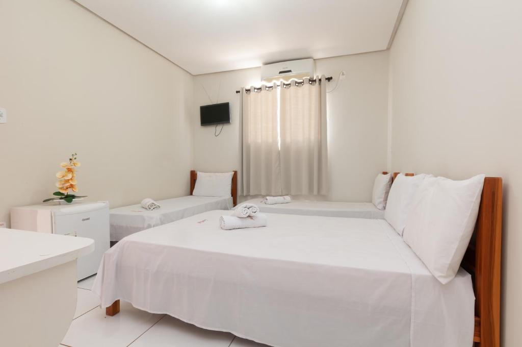 a white bedroom with a bed and a tub at Lapa Hotel in Bom Jesus da Lapa
