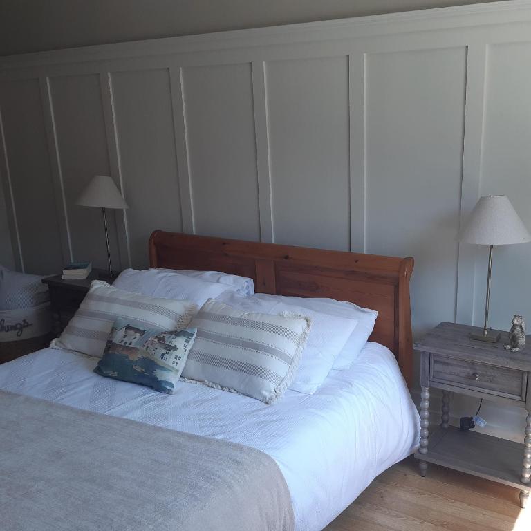 a bedroom with a bed with white sheets and pillows at Grovehouse in Portstewart
