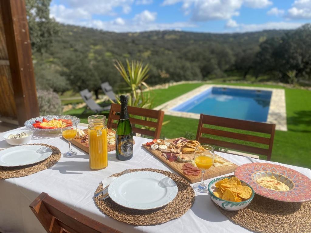 una mesa con platos de comida y bebida y una piscina en La Siesta del Naranjo, en Monesterio