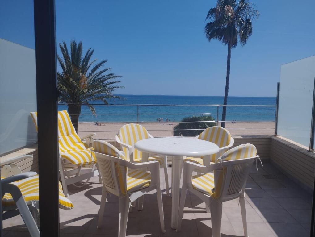 een tafel en stoelen op een balkon met uitzicht op het strand bij Urbanización Marenia - Las Marinas, Denia in Denia