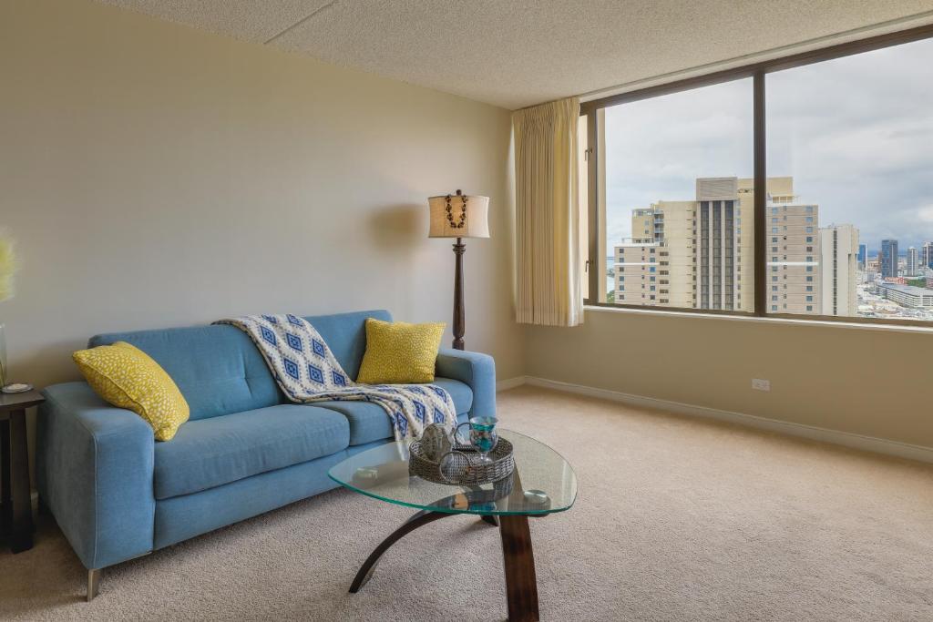 a living room with a blue couch and a large window at Honolulu Condo Stay with Balcony Walk to Beaches! in Honolulu