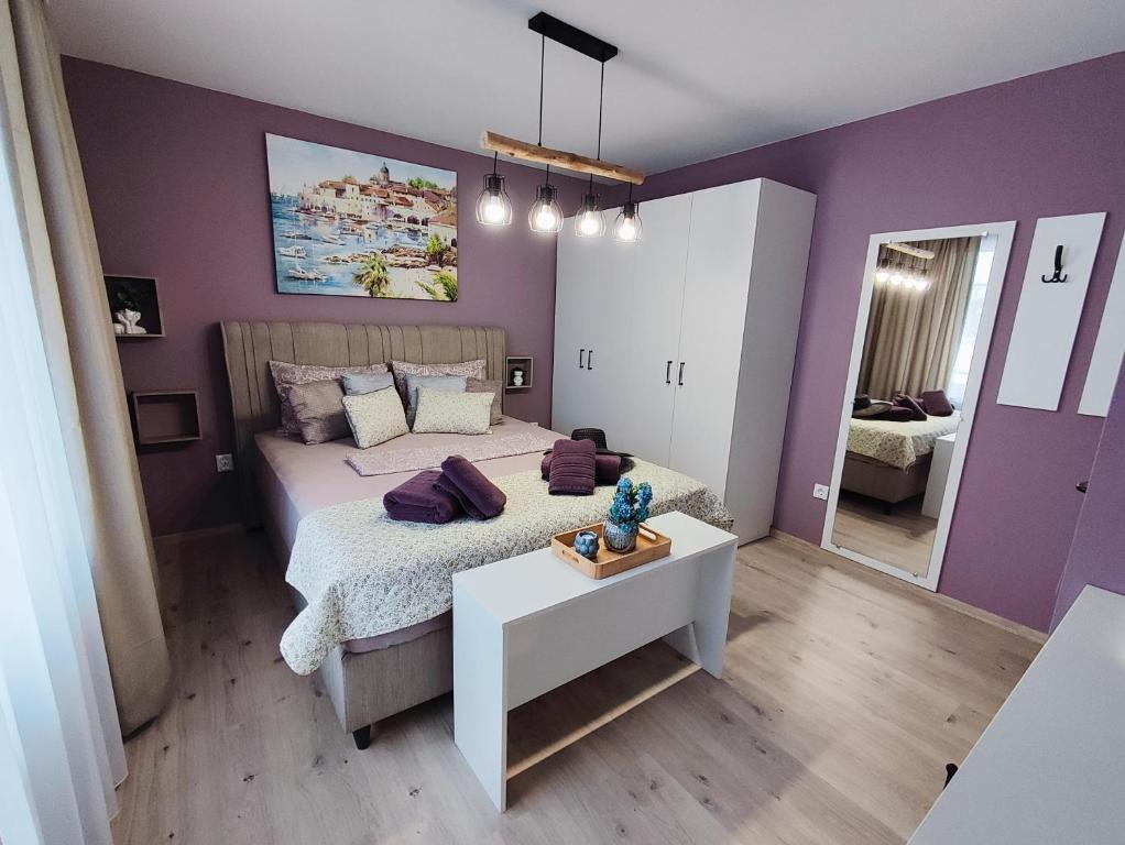 a purple bedroom with a bed and a table at AMORE Obzor in Obzor