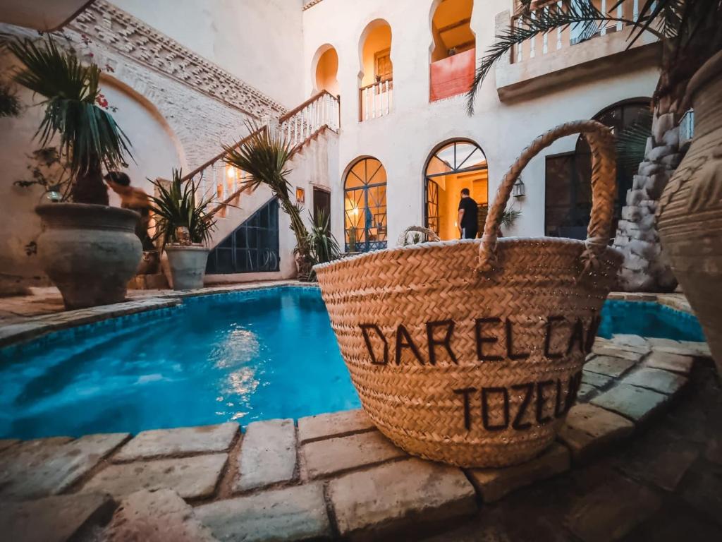a house with a swimming pool and baskets on the floor at Riad Dar El Caid - Palais XIII Siecle in Tozeur