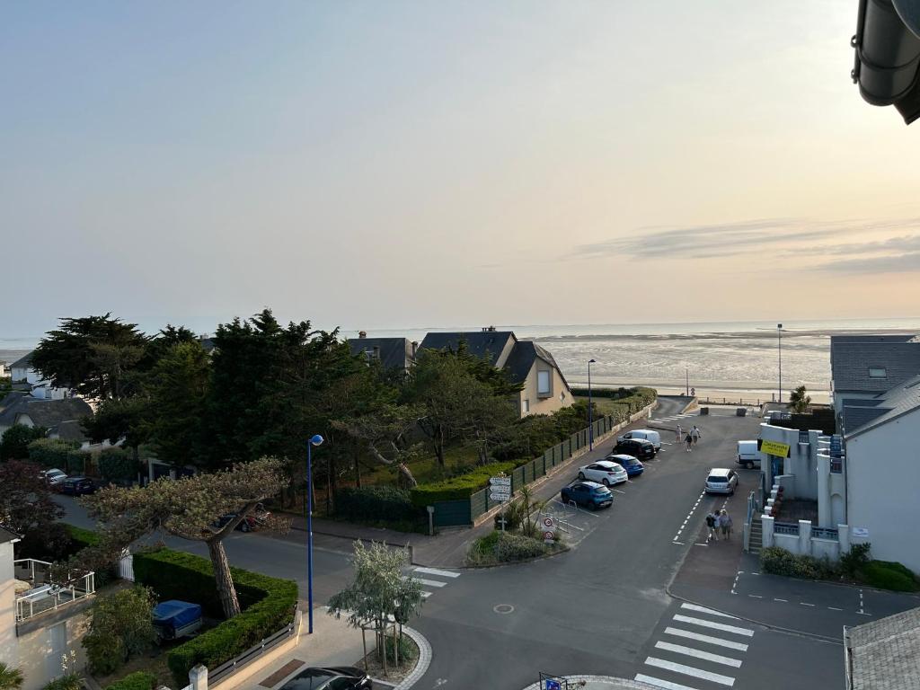 widok na ulicę z samochodami zaparkowanymi na plaży w obiekcie Appartement pour évasion marine à Hauteville sur mer w mieście Hauteville-sur-Mer