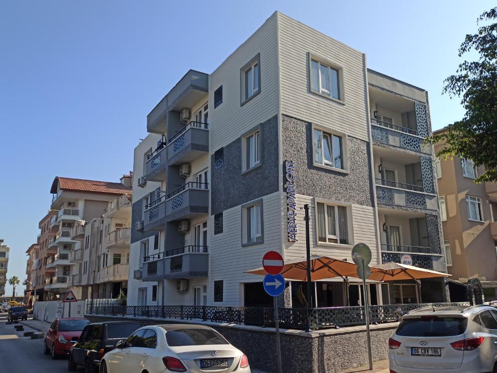 een hoog gebouw met auto's geparkeerd voor het bij Merve Apart Hotel in Alanya