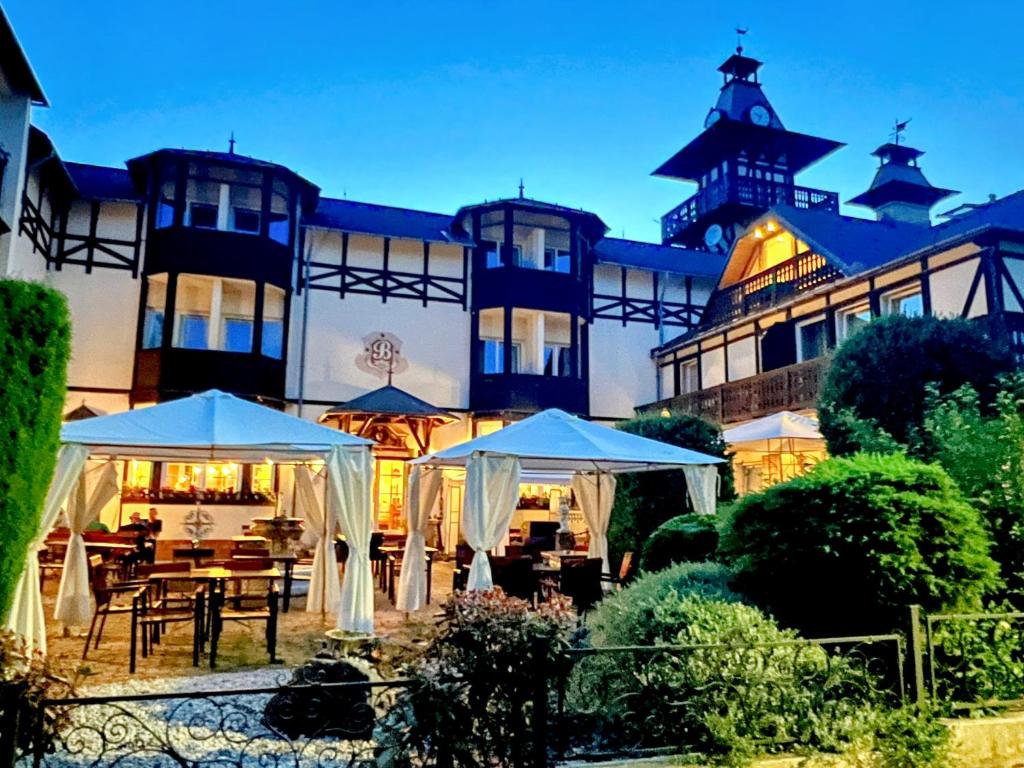 a building with tables and umbrellas in front of it at Schlosshotel Marienbad in Mariánské Lázně