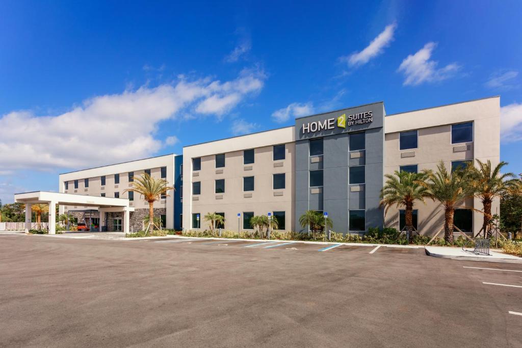 een groot wit gebouw met palmbomen op een parkeerplaats bij Home2 Suites By Hilton Vero Beach I-95 in West Vero Corridor