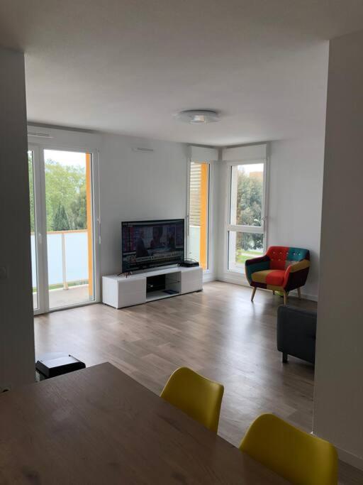 uma sala de estar com uma televisão e uma mesa e cadeiras em Logement neuf proche plage et aéroport em Nice