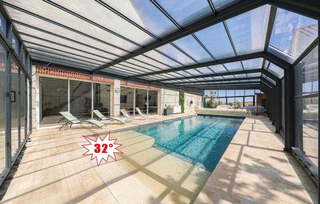 an indoor swimming pool with a glass ceiling at Le Loft de la Grange in Léglantiers