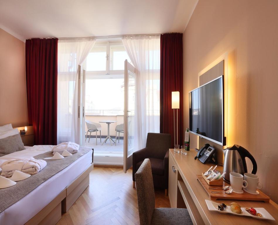 a hotel room with a bed and a desk with a television at Amarilis in Prague
