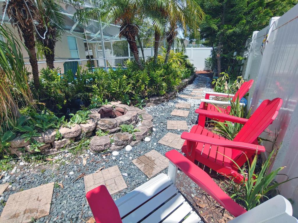a group of red chairs and a bench in a garden at Cozy and Conveniently located Pool Home with Free WiFi in Tampa