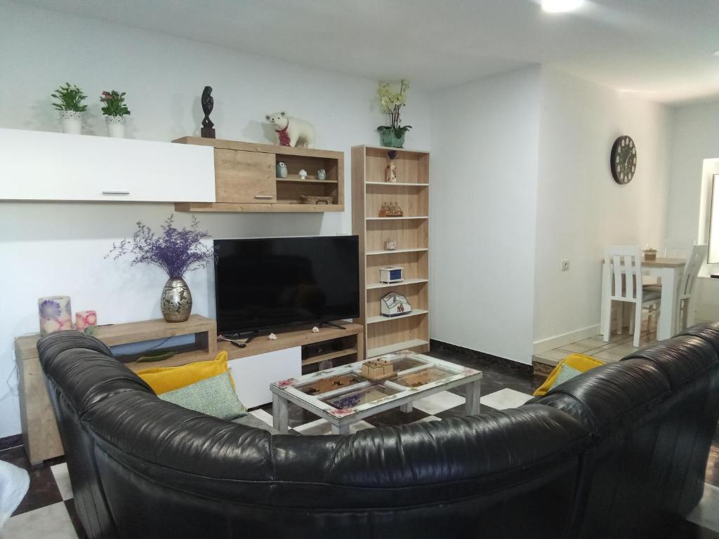 sala de estar con sofá de cuero negro y TV en Acogedor apartamento a 5 minutos de Sanxenxo, en Pontevedra