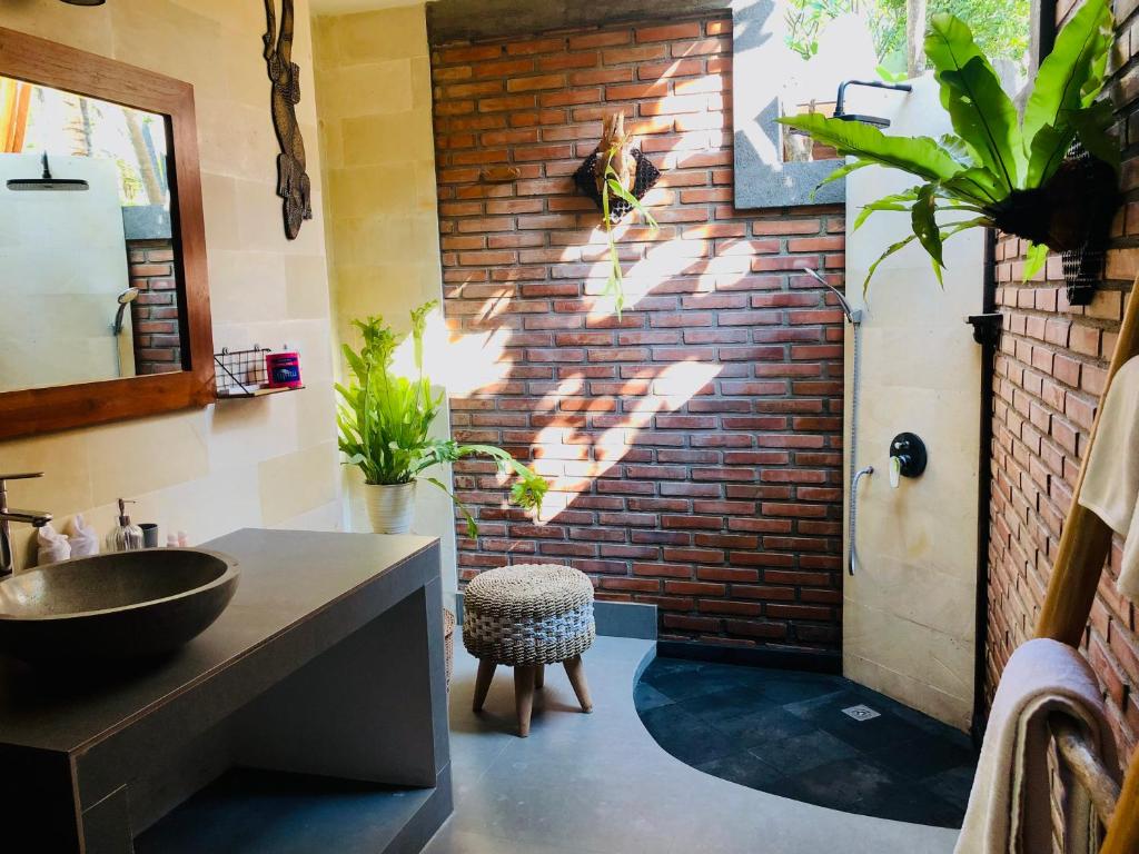 ein Badezimmer mit einem Waschbecken und einer Ziegelwand in der Unterkunft Coco Garden Pool Villas in Kubutambahan