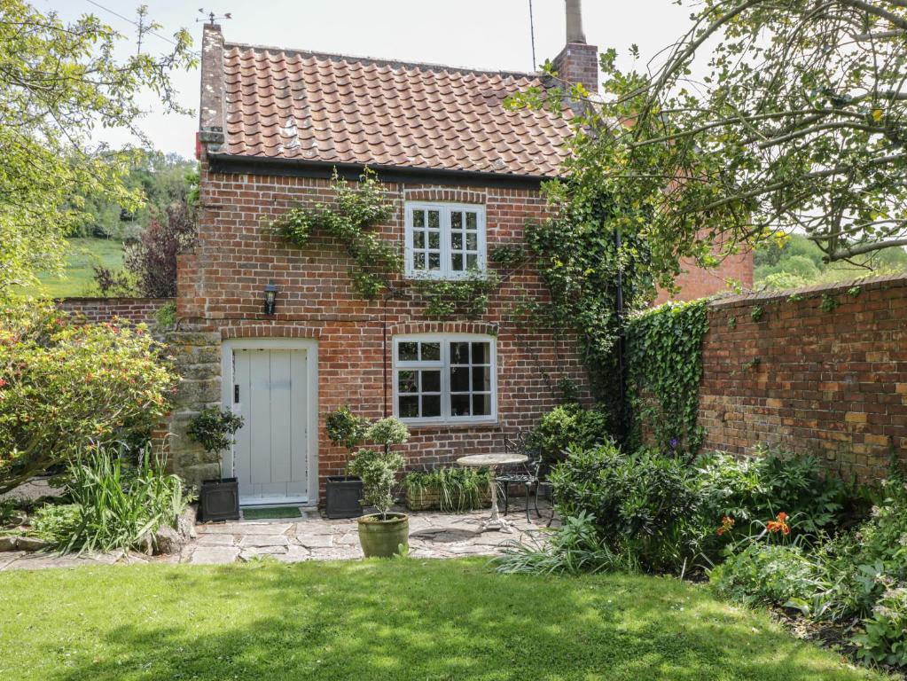 una casa de ladrillo con una puerta blanca y un patio en The Cottage, en Highbridge