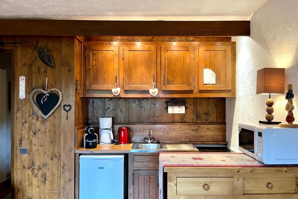 a kitchen with wooden cabinets and a white microwave at Cosy studio with garden and view of Mont Blanc in Saint-Gervais-les-Bains