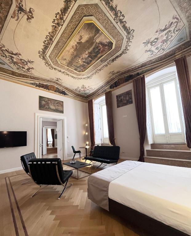 a bedroom with a bed and chairs and a ceiling at Corso Grand suites in Barletta