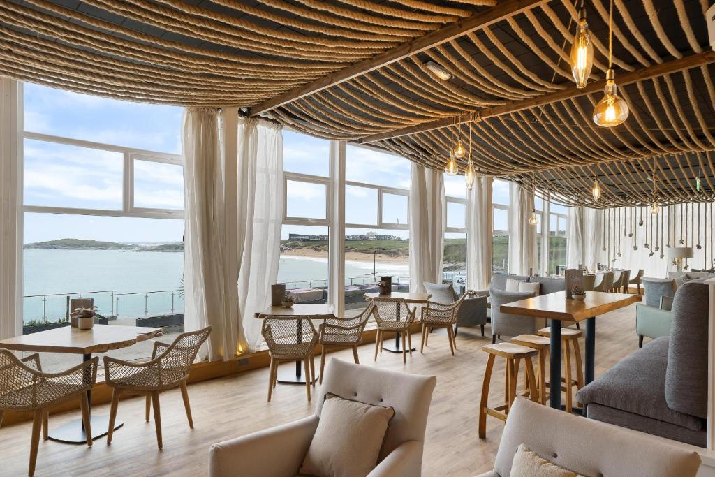 a restaurant with tables and chairs and large windows at Fistral Beach Hotel and Spa - Adults Only in Newquay