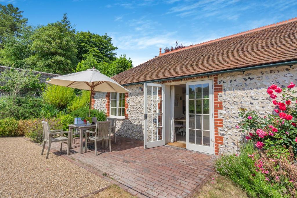 a cottage with an umbrella and a table and chairs at Folly Cottage in Eastdean