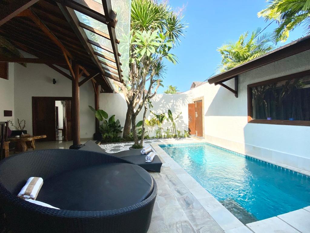 a swimming pool with a black couch next to a house at Belharra Villas Seminyak in Seminyak
