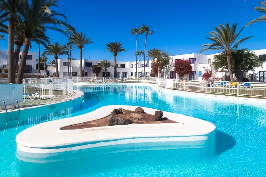 una piscina in un resort con palme di Los Barqueros 24 by Best Holidays Fuerteventura a Corralejo