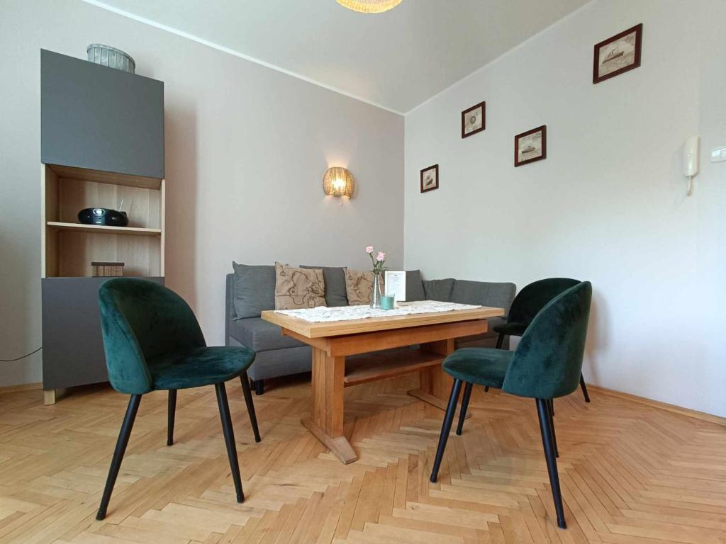 格地尼亞的住宿－Apartament Baltica Nawigator，客厅配有桌子和两把绿色椅子