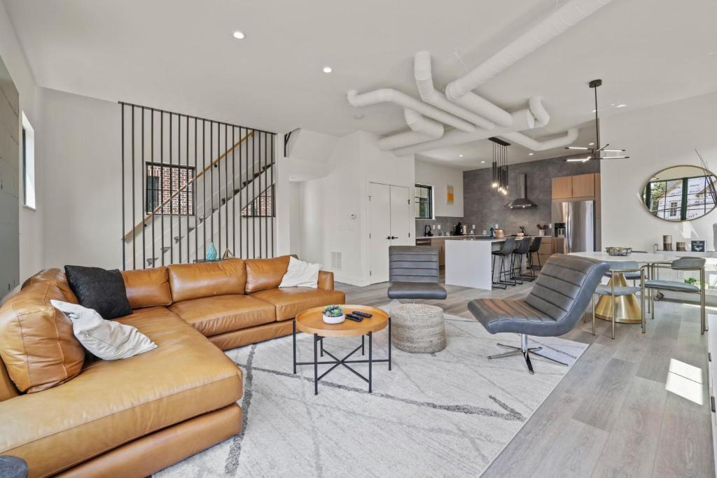 a living room with a brown couch and a kitchen at The Elegant Estate - Modern Home in Columbus in Columbus