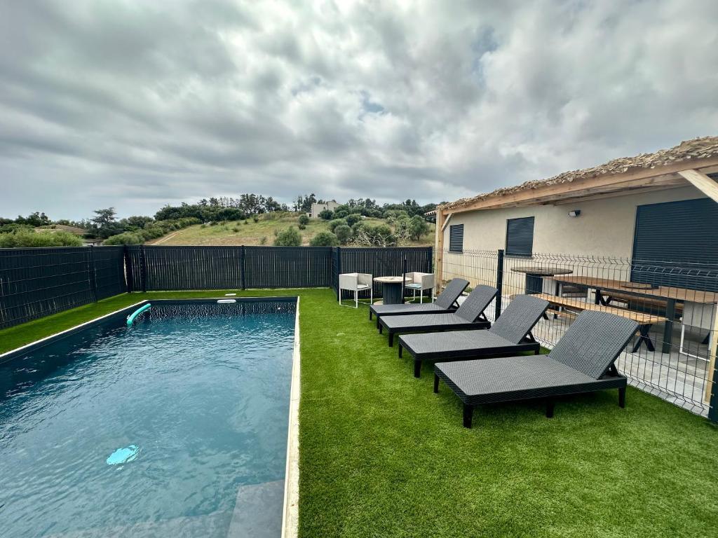 un patio trasero con una piscina con sillas y una mesa en Casa Lamaghjone - Villa T4 avec piscine chauffée à 3,5km de la mer, en Aléria