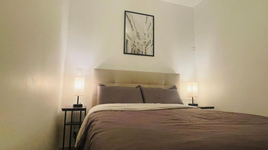 a bedroom with a bed and two lamps on tables at Joli 2 pièces tout confort Paris Parc des expositions Villepinte in Villepinte