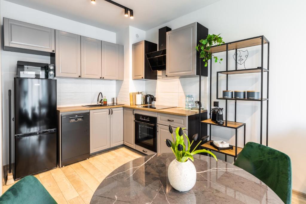 a kitchen with a table and a black refrigerator at Green Harmony Apartment in Sosnowiec