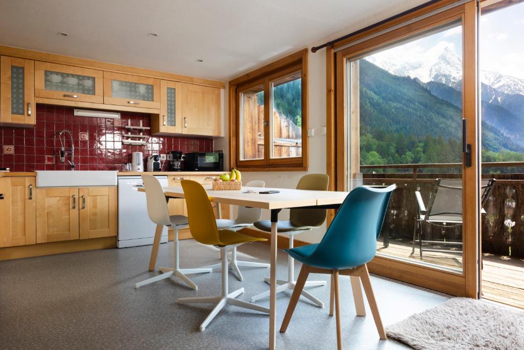 een keuken met een tafel en stoelen en uitzicht op de bergen bij La Snaille des Planards in Chamonix-Mont-Blanc