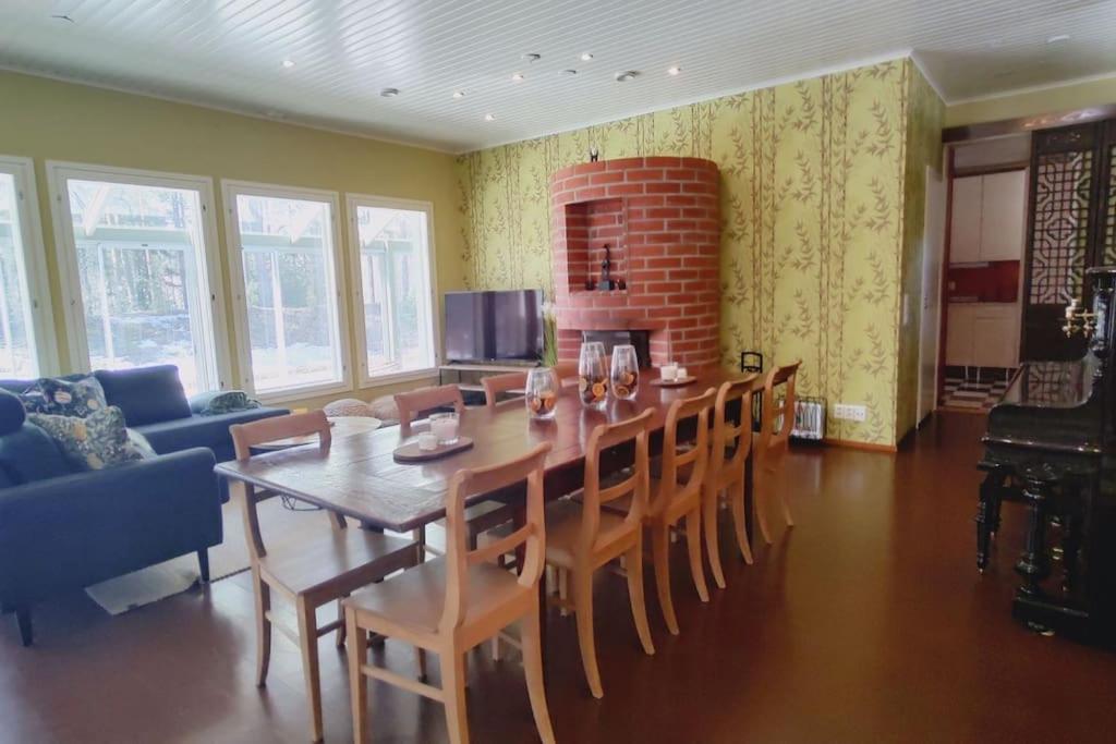 a dining room with a long table and chairs at Villa Vihreä Yyteri in Pori
