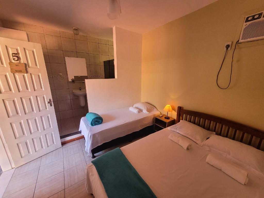 a room with two beds and a bathroom with a shower at Pousada Villa Coelho in Camaçari