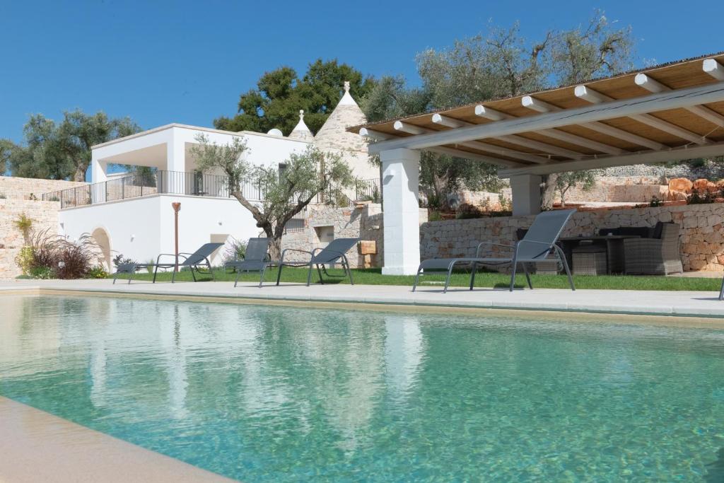 a swimming pool with chairs and a house at Trullo Mamamè in Cisternino