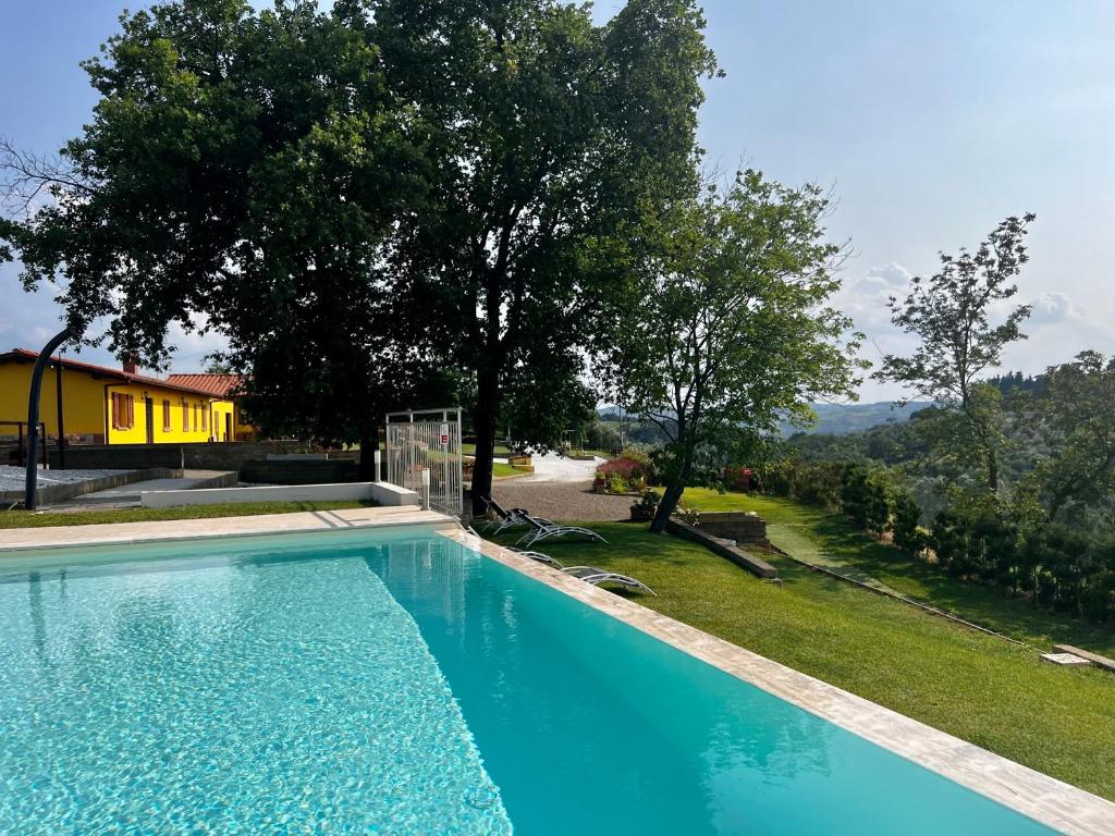 a large blue swimming pool in a yard with trees at Colle Del Sole in Lastra a Signa