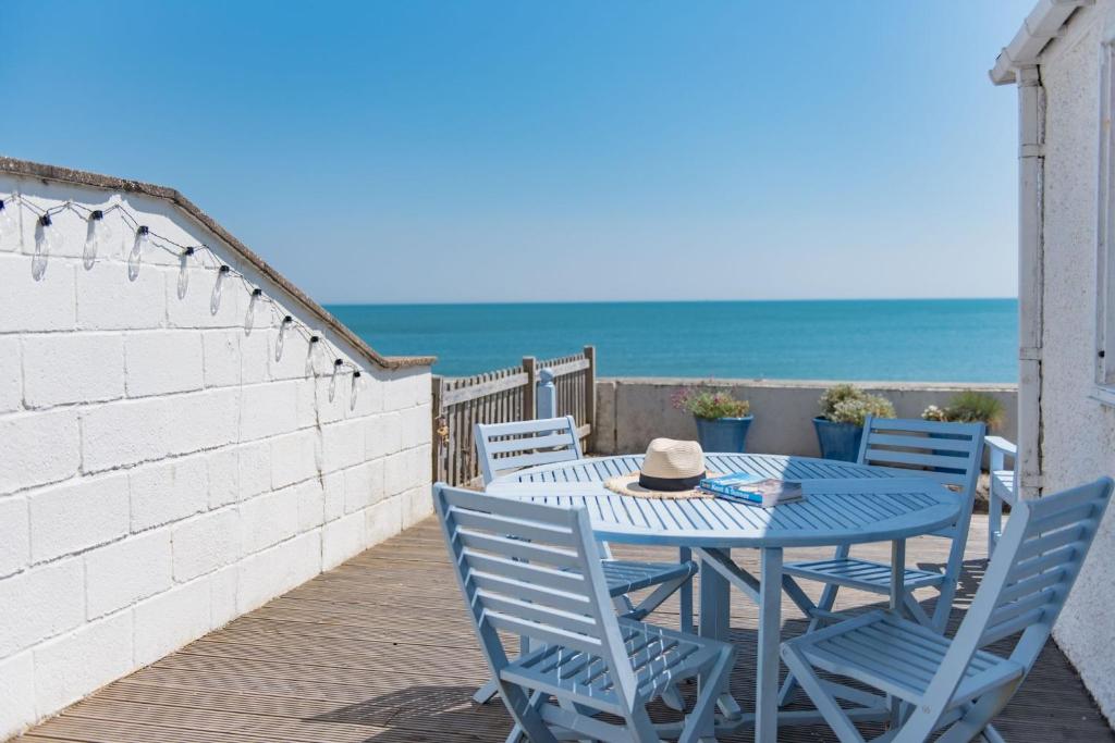 a blue table and chairs on a deck with the beach at Wave Cottage by Bloom Stays in Sandgate
