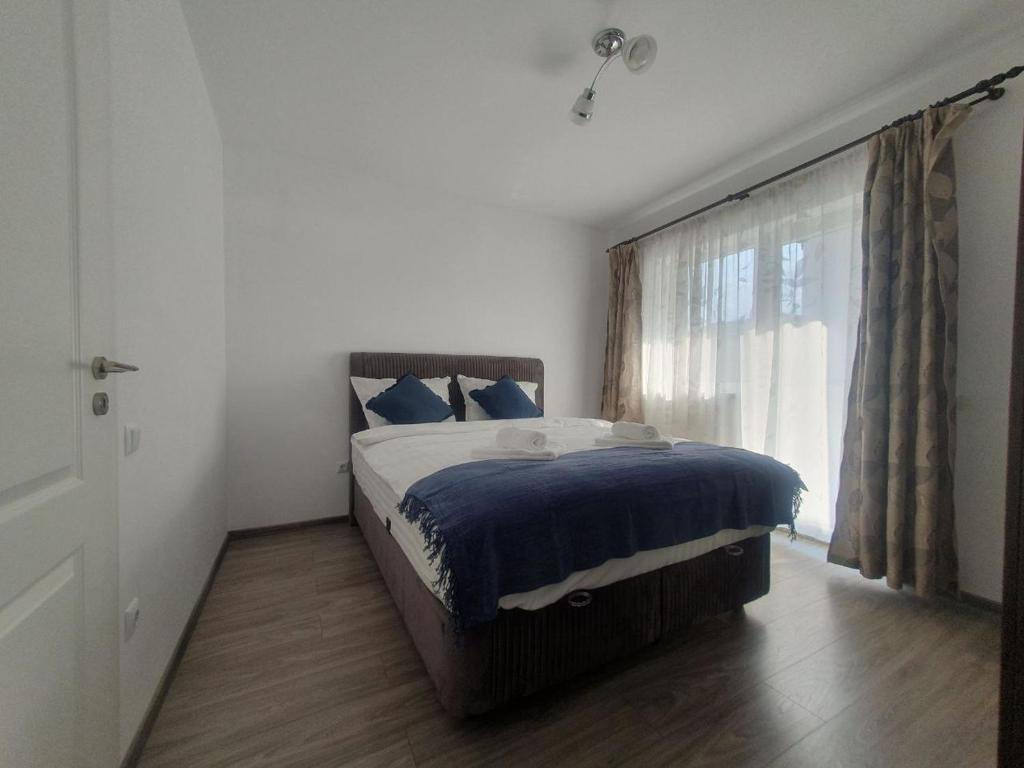 una camera da letto con un letto con lenzuola blu e una finestra di Flat in Sibiu 20 min to Sibiu Airport a Sibiu