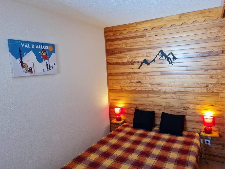 a bedroom with a wooden wall with a bed and two lamps at Appartement 1 chambre, calme, vue dégagée, La Foux in La Foux