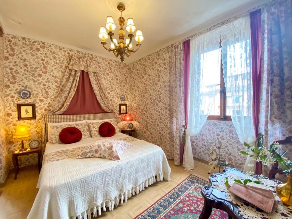 a bedroom with a bed and a chandelier at Camera Romantica con Giardino in Dimora Storica - B&B Palazzo Robicci in Castiglion Fiorentino