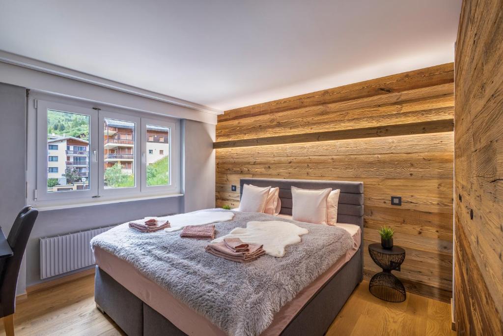 a bedroom with a large bed with a wooden wall at Lucky Fox in Leukerbad