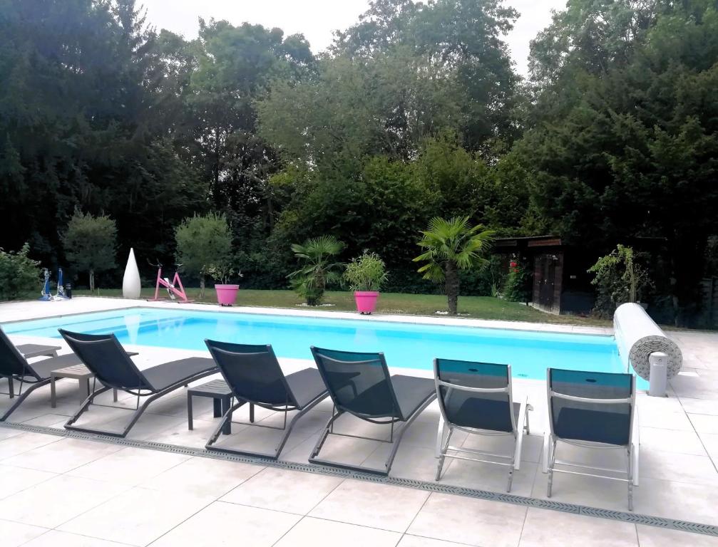 un grupo de sillas sentadas junto a una piscina en Aux Couleurs d'Alsace en Ostwald