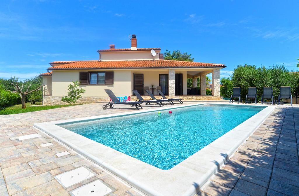 a villa with a swimming pool in front of a house at House Liznjan 2273 in Ližnjan