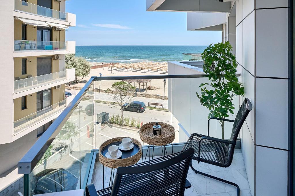 a balcony with two chairs and a table and the ocean at Infinity by Sea Apartment Beach Resort - parking in Mamaia