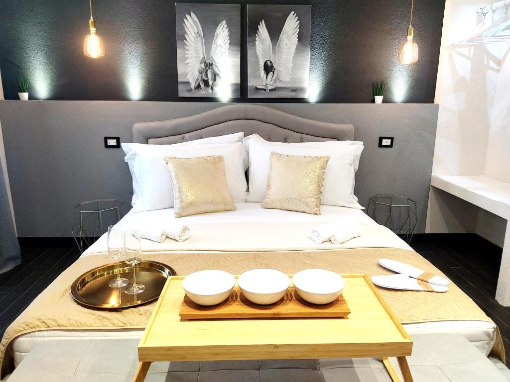 a bed with a tray and bowls on it at Ti Scialíi Suites Rooms and Relax in Pachino