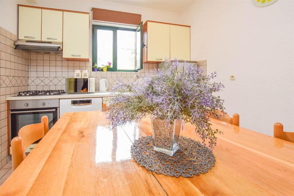 eine Küche mit einem Holztisch mit einer Vase aus Blumen in der Unterkunft Ozzy in Biograd na Moru
