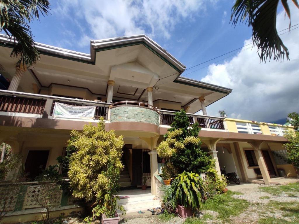 a large house with a balcony and trees at Riverside at Aninuan Accommodation and Food in Puerto Galera