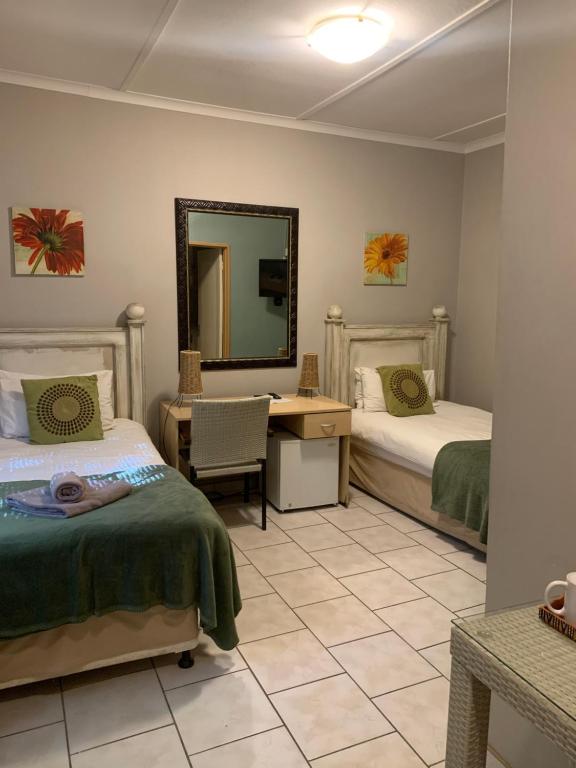 a bedroom with two beds and a desk and a mirror at Hotel Pension Casa Africana in Windhoek