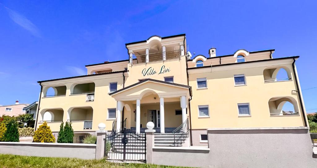 un bâtiment jaune avec un panneau sur lequel figure un panneau dans l'établissement Villa Livi - Luxury sea view appartments, à Medulin