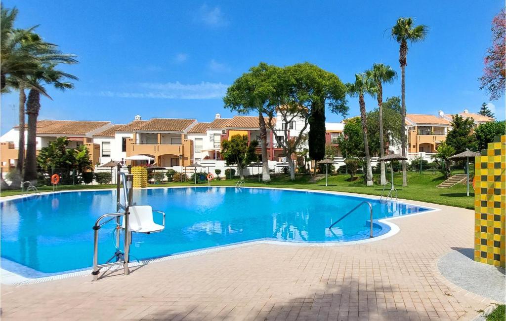a swimming pool in a villa with palm trees and houses at Cozy Apartment In Chiclana De La Front, With Kitchen in Novo Sancti Petri