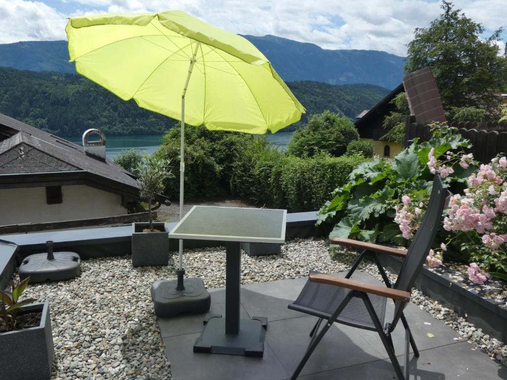 ein gelber Regenschirm auf einer Terrasse mit einem Tisch und Stühlen in der Unterkunft Haus Harmonie in Millstatt
