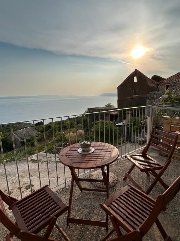 a patio with a table and two chairs and the ocean at Stone house Kurtić stara Podgora in Podgora